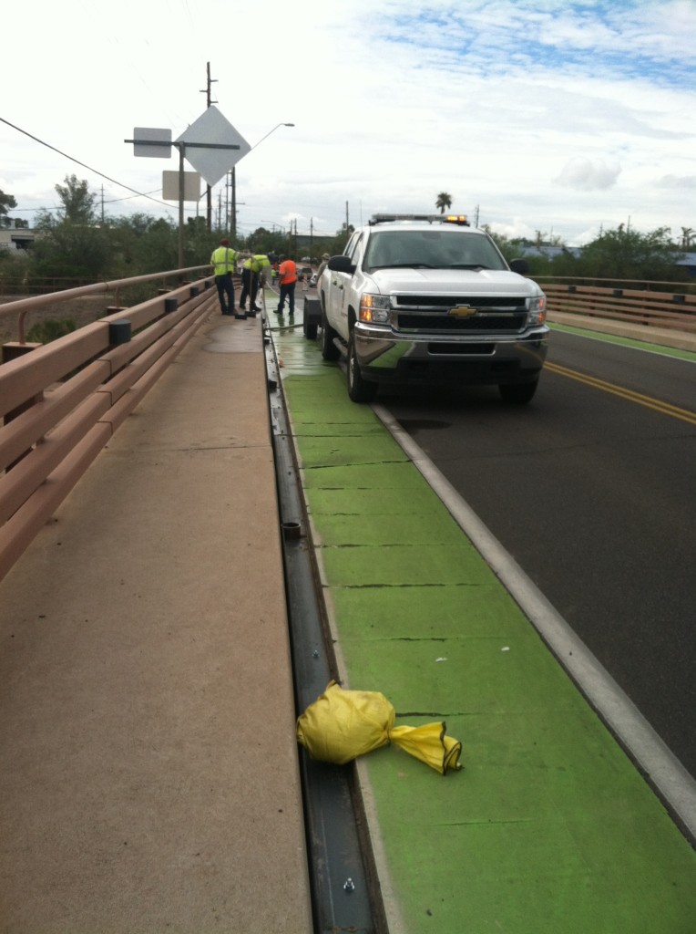 The gap is clearly visible between the green bike lane and the curb.  Crews power washing in preparation of the new concrete.